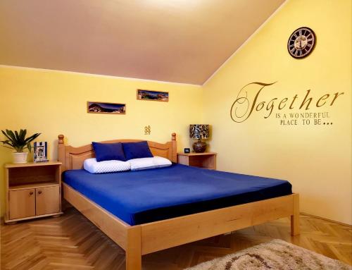 a bedroom with a bed with blue sheets and a sign at Apartman VILLA Cacak in Čačak