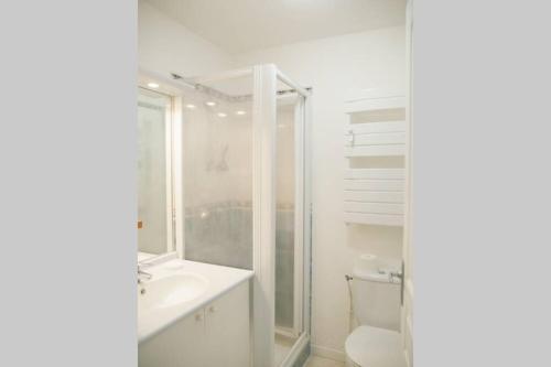 La salle de bains blanche est pourvue de toilettes et d'un lavabo. dans l'établissement Studio situé dans le centre de Saint Philibert, à Saint-Philibert