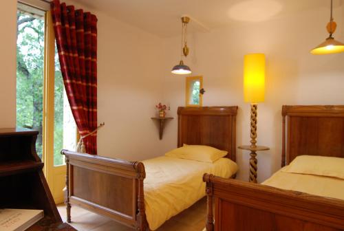 sypialnia z 2 łóżkami i oknem w obiekcie La maison jaune w mieście La Roque-sur-Pernes