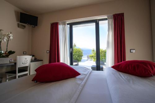 1 dormitorio con 2 camas con almohadas rojas y ventana en Agritur Acetaia Gourmet&Relax, en Tenno