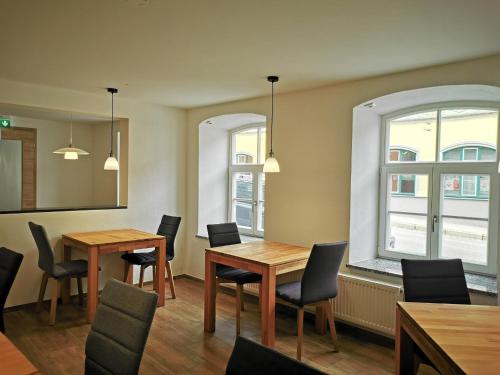 a dining room with two tables and chairs and two windows at Pension unterm Schlossturm in Haag in Oberbayern