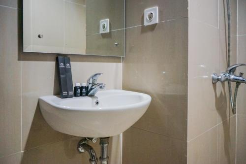 a bathroom with a white sink and a shower at Cozy and Sweet Studio at Paramount Skyline Apartment By Travelio in Tangerang