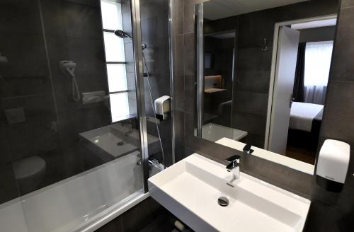 a bathroom with two sinks and a mirror at Hôtel Des Quatrans in Caen