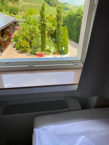 a window with a view of a garden from a bedroom at Garni San Paolo in Appiano sulla Strada del Vino