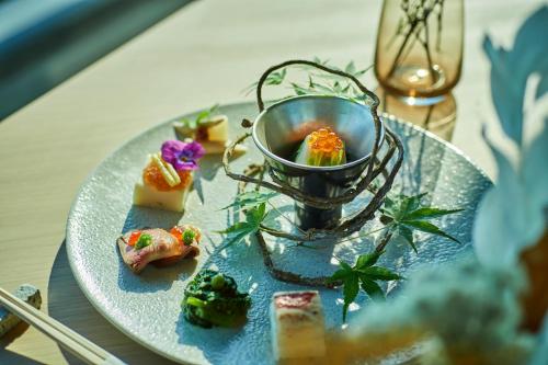 a plate of food with sushi on a table at ANDO HOTEL NARA Wakakusayama -DLIGHT LIFE & HOTELS- in Nara