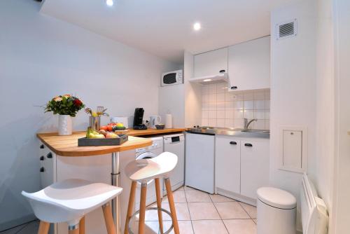 a kitchen with white cabinets and a table and stools at Appartement La Terrasse sur cour in Colmar