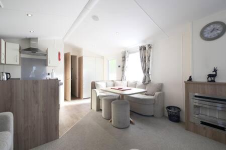 een woonkamer met een tafel, een bank en een klok bij Edinburgh - Seton Sands - Rio Caravan - Pet Friendly in Edinburgh