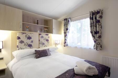 - une chambre avec un grand lit blanc et une fenêtre dans l'établissement Edinburgh - Seton Sands - Rio Caravan - Pet Friendly, à Édimbourg