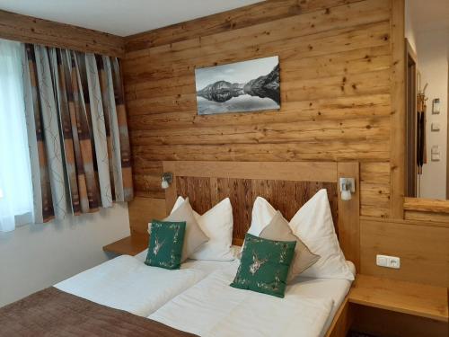 a bedroom with a bed with white sheets and green pillows at Pension Ballwein in Salzburg