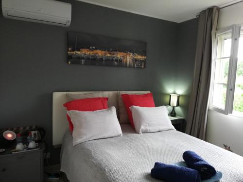 a bedroom with a bed with red and white pillows at Chambre d'hôtes à 5mn des plages in Patrimonio