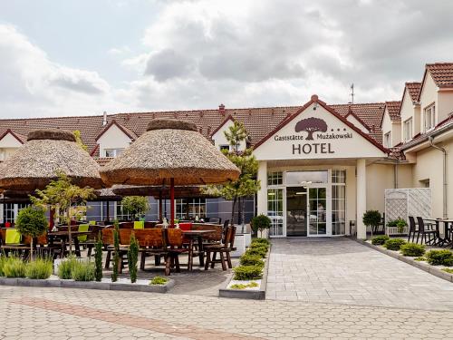 a hotel with a patio with tables and umbrellas at Hotel Mużakowski in Łęknica