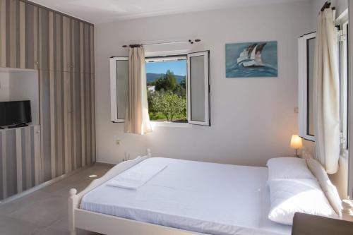 a white bedroom with a bed and a window at Boursinos cozy apartments by Imagine Lefkada in Lefkada Town
