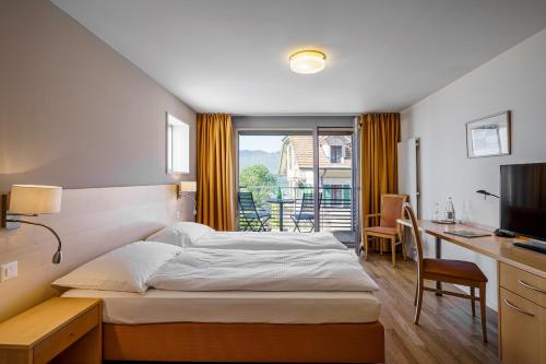 a bedroom with a bed and a desk and a window at Schönbühl Hotel & Restaurant Lake Thun in Thun