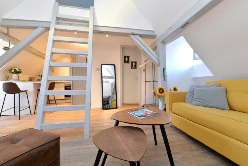 - un salon avec un canapé jaune et une échelle dans l'établissement Appartement La petite terrasse sur les toits, à Colmar