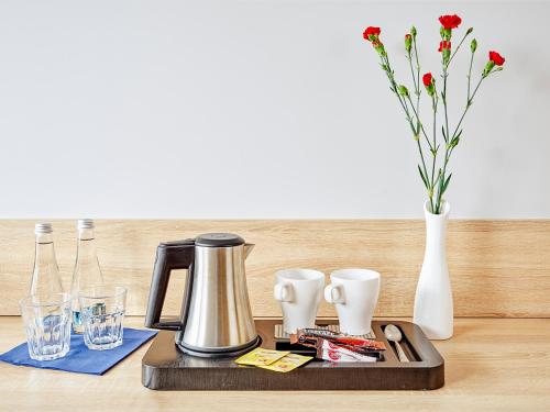 a coffee maker on a tray with a vase and glasses at Hotel Mużakowski in Łęknica