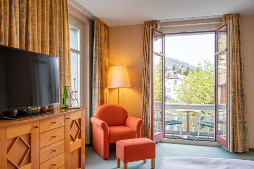 a living room with a television and a large window at Schönbühl Hotel & Restaurant Lake Thun in Thun
