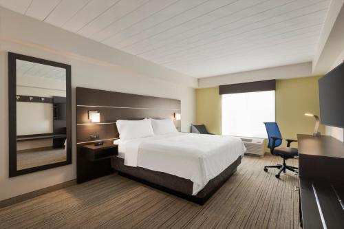 a hotel room with a bed and a mirror at Holiday Inn Express Hotel & Suites Fort Myers East - The Forum by IHG in Fort Myers