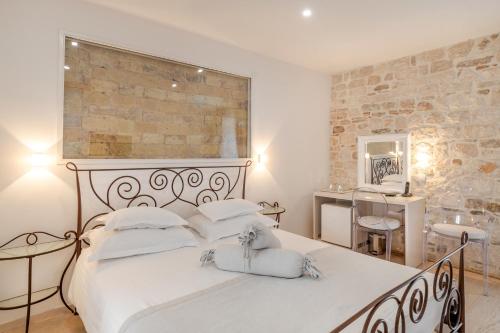 ein Schlafzimmer mit einem großen weißen Bett und einer Steinmauer in der Unterkunft Palace Tartaglia in Split