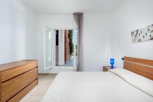 una camera da letto bianca con un letto e una finestra di Villa Marconi Apartment 4 a Golfo Aranci