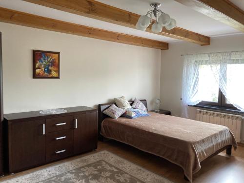 a bedroom with a bed and a dresser and a ceiling at Kornatka Hajnówka Pokoje Puszcza Białowieska in Hajnówka