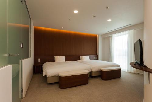a bedroom with a large bed and a flat screen tv at Daiwa Roynet Hotel Numazu in Numazu