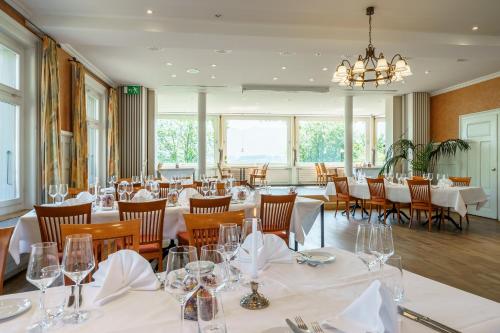 a restaurant with white tables and chairs and a chandelier at Schönbühl Hotel & Restaurant Lake Thun in Thun