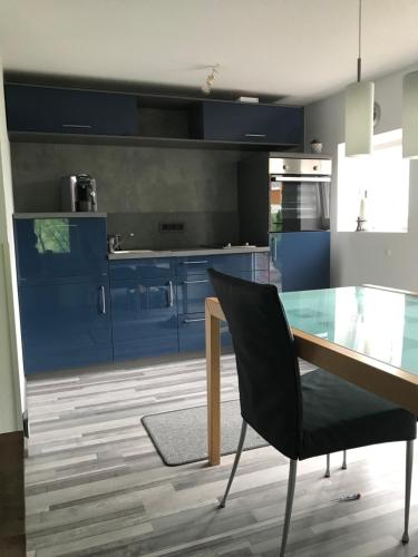 Una cocina con gabinetes azules y una mesa de vidrio y una silla. en Haus Friedel Überlingen am Bodensee, en Überlingen