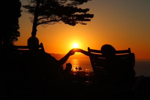 Zwei Leute sitzen auf einer Bank und beobachten den Sonnenuntergang. in der Unterkunft Casa Particular in Caravia