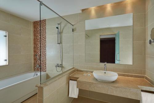 a bathroom with a sink and a tub and a mirror at Steigenberger Aqua Magic Red Sea in Hurghada