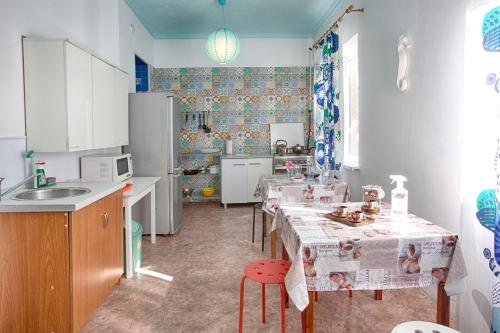 a kitchen with a table and chairs and a refrigerator at Chernomor Guest House in Vityazevo