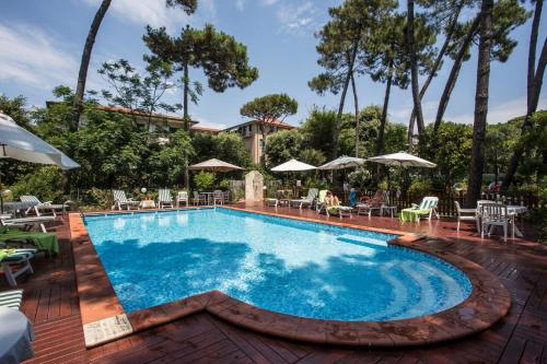 a pool with chairs and umbrellas on a patio at Piccolo Hotel in Forte dei Marmi