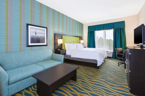 a hotel room with a bed and a couch at Holiday Inn Express & Suites Southport - Oak Island Area by IHG in Oak Island
