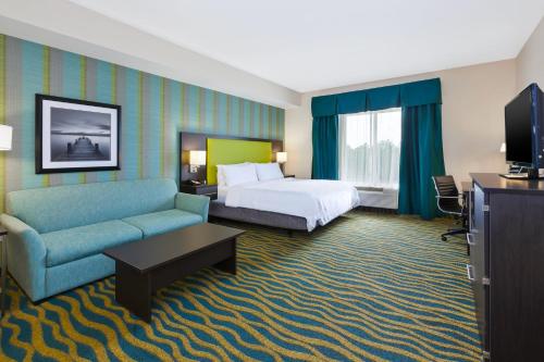 a hotel room with a bed and a couch at Holiday Inn Express & Suites Southport - Oak Island Area by IHG in Oak Island