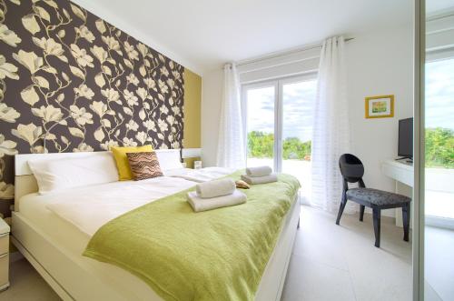 a bedroom with a large bed with a green blanket at Villa Helines***** in Linardići