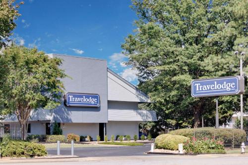 a building with two blue signs on the side of it at Travelodge by Wyndham College Park in Atlanta