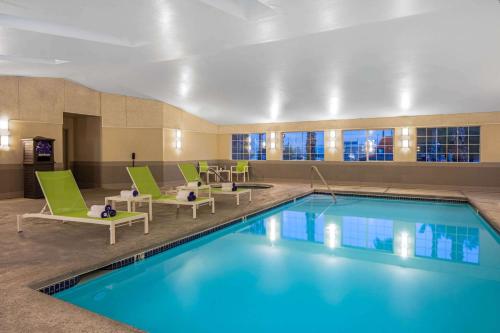 a pool in a hotel room with green chairs and a pool at La Quinta Inn & Suites by Wyndham Las Vegas Nellis in Las Vegas