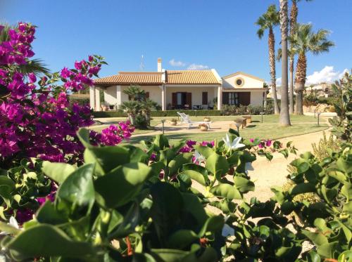 a house with palm trees and purple flowers at Borgo della Luna in Birgi Vecchi