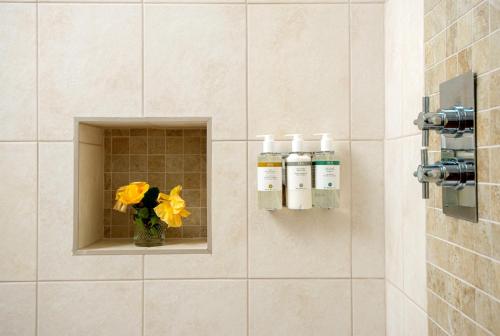 a bathroom with two bottles of soap and a vase with flowers at Barrow Hill Barns in Petersfield