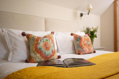a book sitting on top of a bed with pillows at Barrow Hill Barns in Petersfield