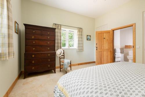 a bedroom with a bed and a dresser and a bathroom at Barrow Hill Barns in Petersfield
