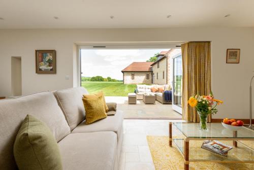 a living room with a couch and a glass table at Barrow Hill Barns in Petersfield