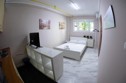 a living room with a white couch and a tv at Xsoma Flats "Studio" in Thessaloniki