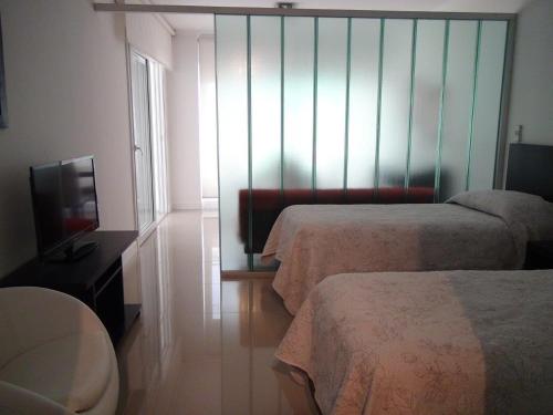 a hotel room with two beds and a television at Green Park Punta 2 in Punta del Este