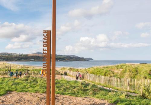 a sign on a beach with the ocean in the background at Joyce's Carndonagh Inishowen in Carndonagh