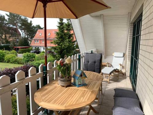 uma mesa de madeira numa varanda com um guarda-chuva em Schippers Butz strandnah mit Whirpool em Ostseebad Karlshagen