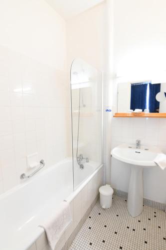 a white bathroom with a tub and a sink at Hôtel Restaurant Du Château in Josselin