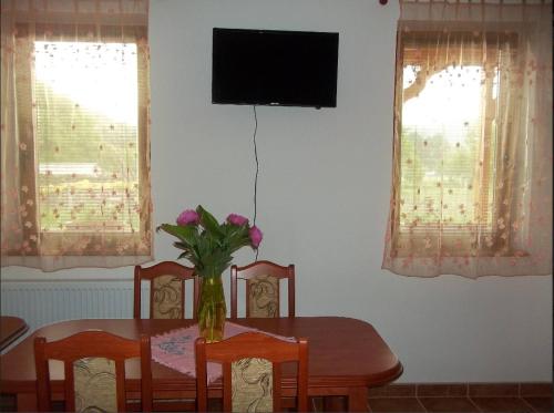 a dining room table with a vase of flowers on it at Szikla Vendégház in Istenmezeje