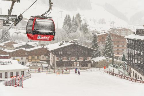 a ski lift with skiers on a snow covered slope at Hotel Pinzgauerhof - Inclusive Evening Dinner in Saalbach Hinterglemm