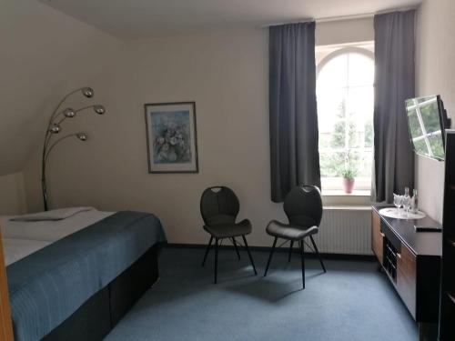 a bedroom with two chairs and a bed and a window at Gasthof-Hotel Biedendieck in Warendorf