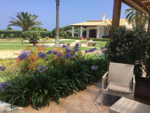 a patio with a garden with flowers and a chair at Borgo della Luna in Birgi Vecchi